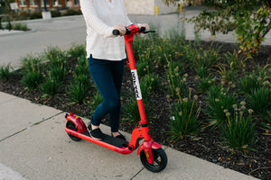 Woman Riding GOTRAX Red Apex Electric Scooter for Adults on a sidewalk
