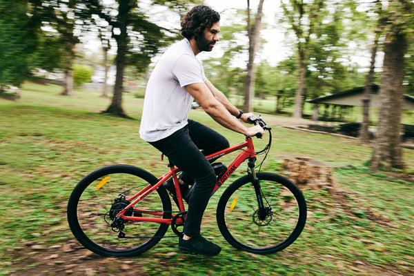Man riding a GOTRAX Traveler All-Terrain Electric Bike for Adults with Front Wheel Suspension through the woods