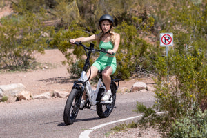 Woman riding GOTRAX White F2 Foldable Electric Bike for Adults with Front Wheel Suspension