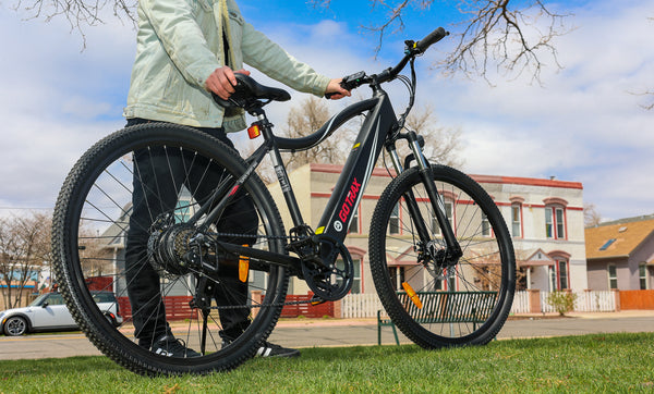 Man holding GOTRAX Black Alpha XL Electric Bike for Adults with Front Wheel Suspension in a park