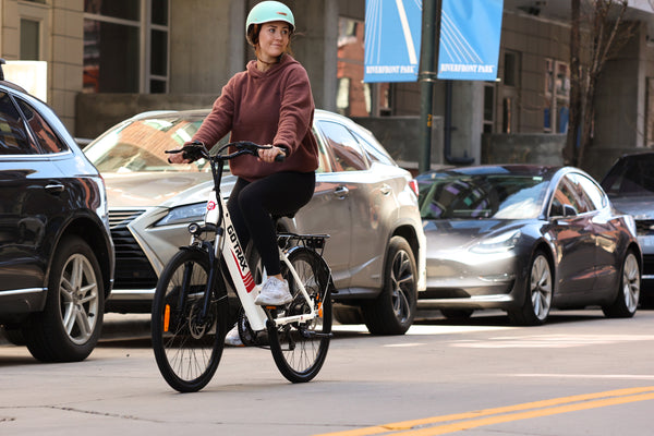 Woman riding GOTRAX White Endura Step-Through Electric Bike with Front Wheel Suspension on a city street