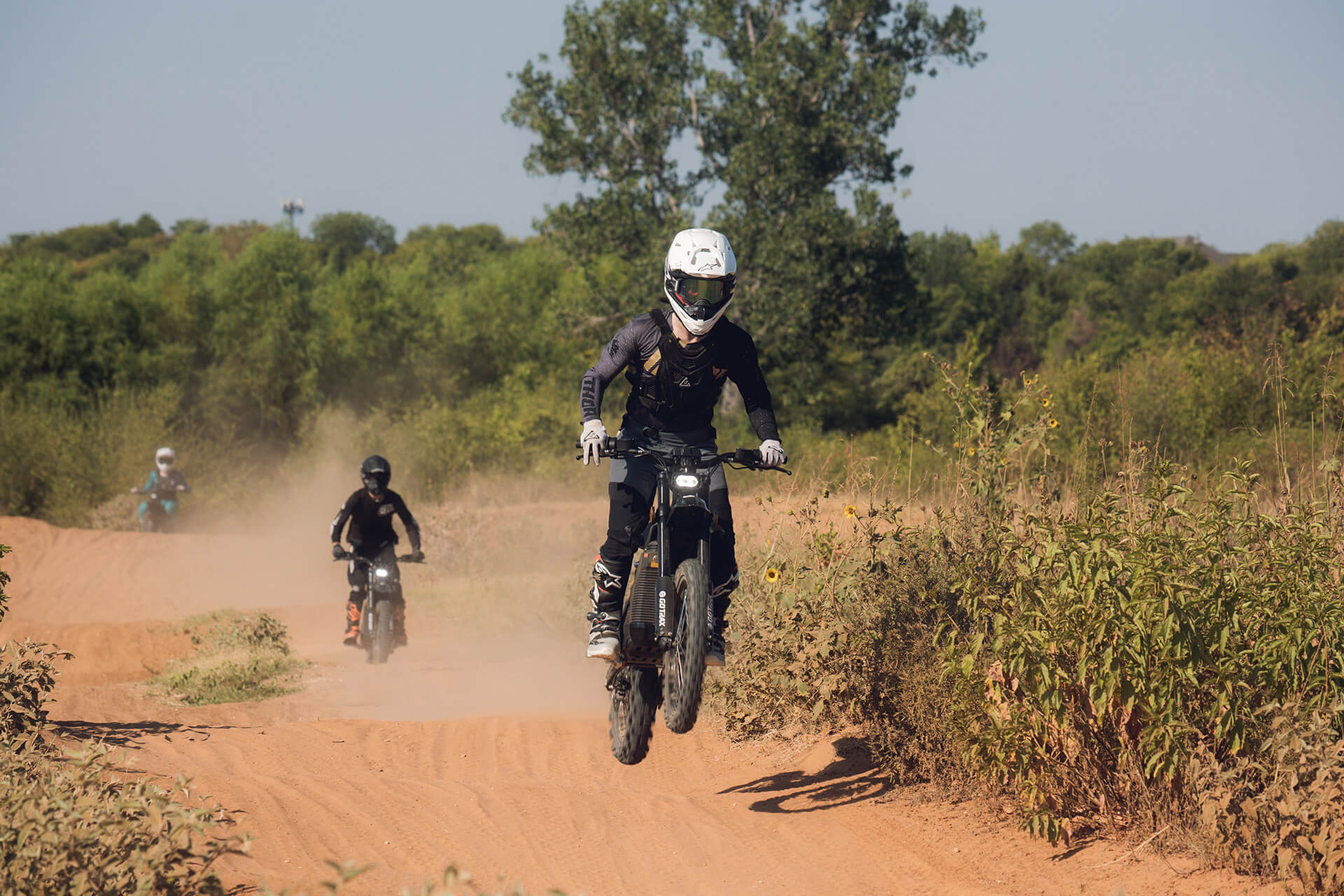 People riding on GOTRAX Everest Electric Dirt Bikes on a Dirt Track