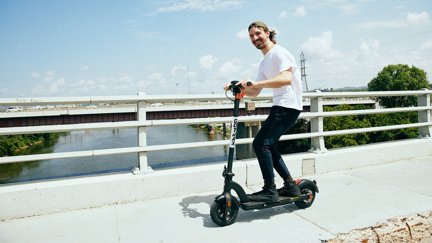 Man riding GOTRAX Black G3 Commuter Electric Scooter for Adults on a Bridge