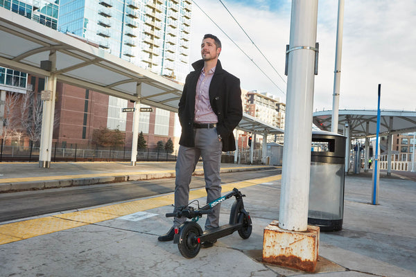 Man standing next to a GOTRAX GMAX Ultra Commuter Electric Scooter in the Folded Position