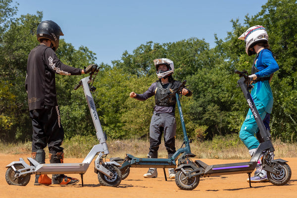 People standing with GOTRAX GX1, GX2, and GX3 Performance Series Electric Scooters