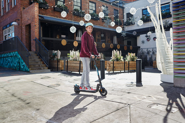A man riding a GOTRAX Black Apex Foldable Entry Level Electric Scooter for Adults