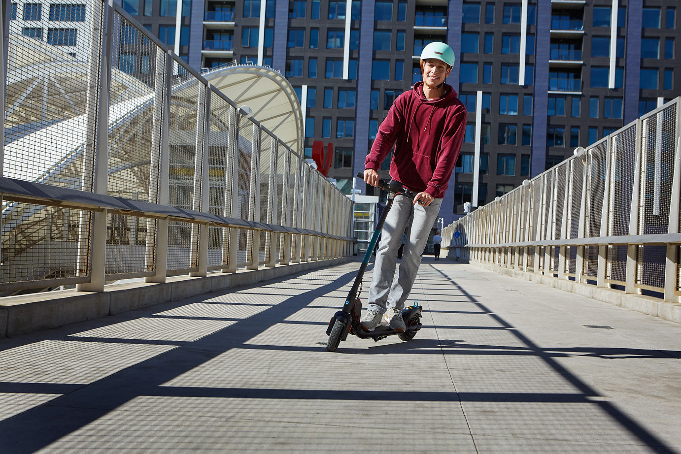 Man riding an Entry Level GOTRAX Black Apex Electric Scooter For Adults in Downtown