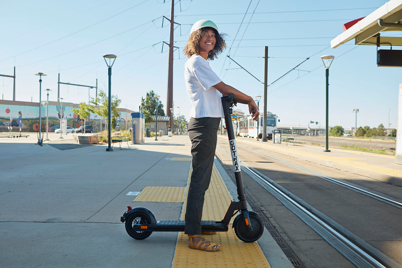 Woman with a GOTRAX Black XR Elite Best Electric Scooter For Adults waiting at a Train Station