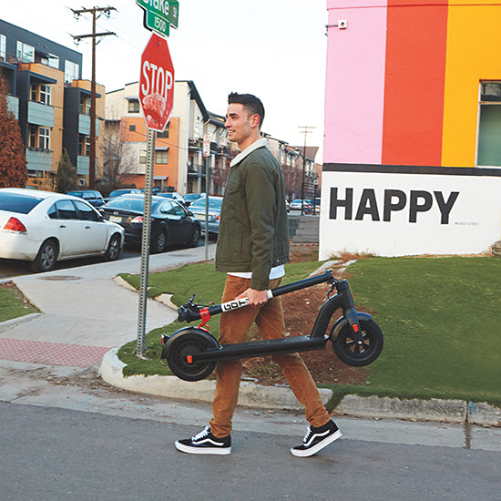 Man carrying GOTRAX Black G4 Electric Scooter for Adults in the Folded Position